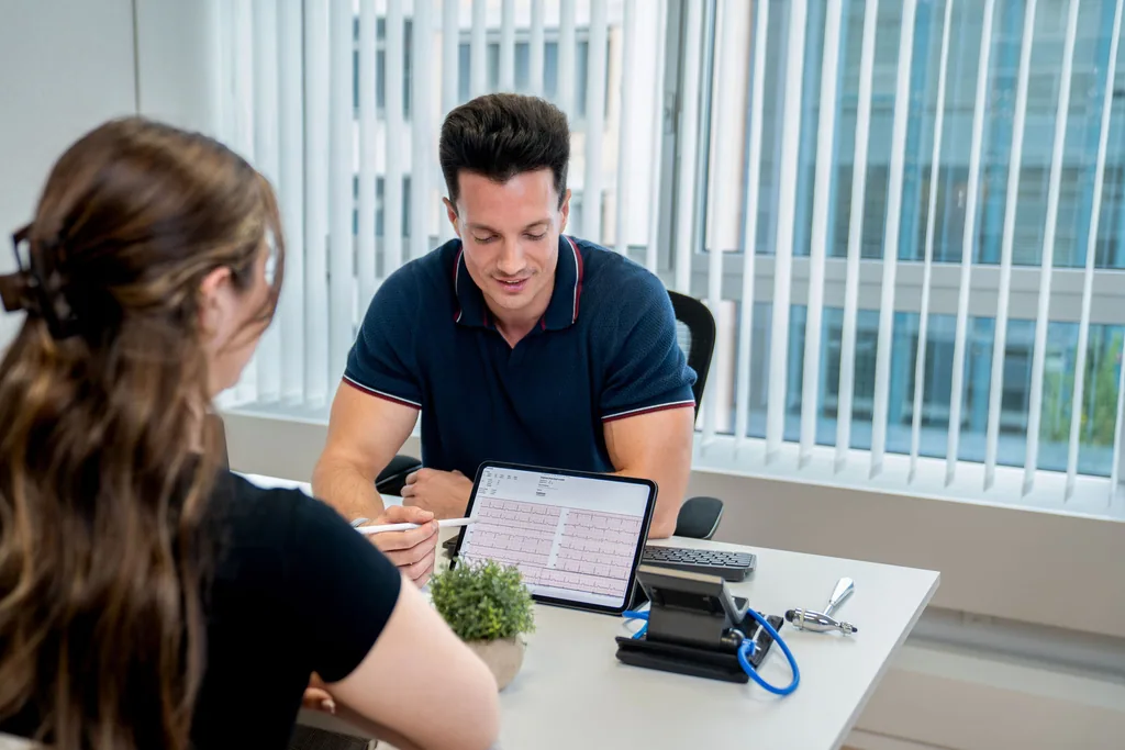Arzt bespricht ein EKG auf dem Tablet mit einer Patientin